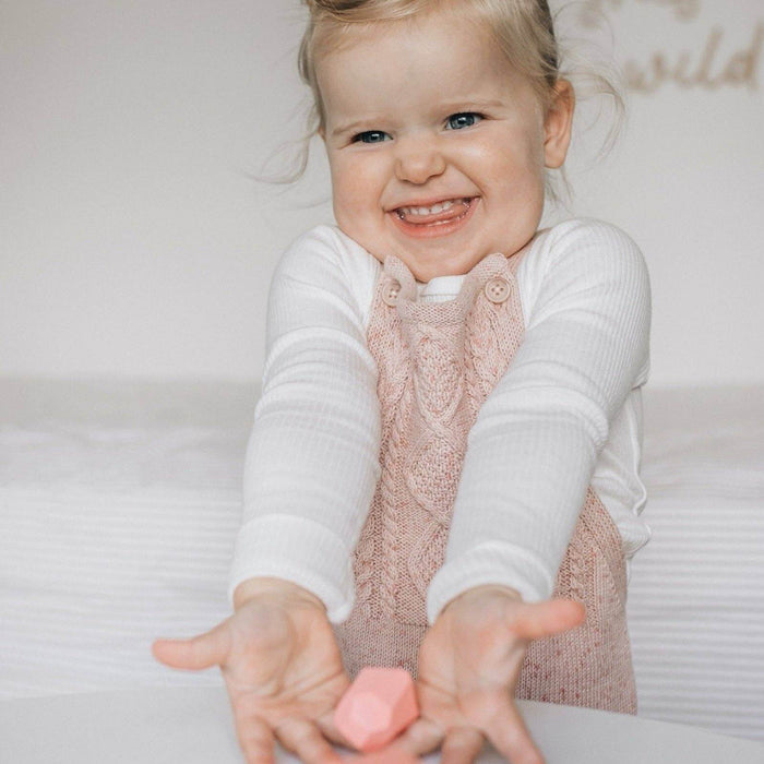 Child holding a pink toy with a plain background