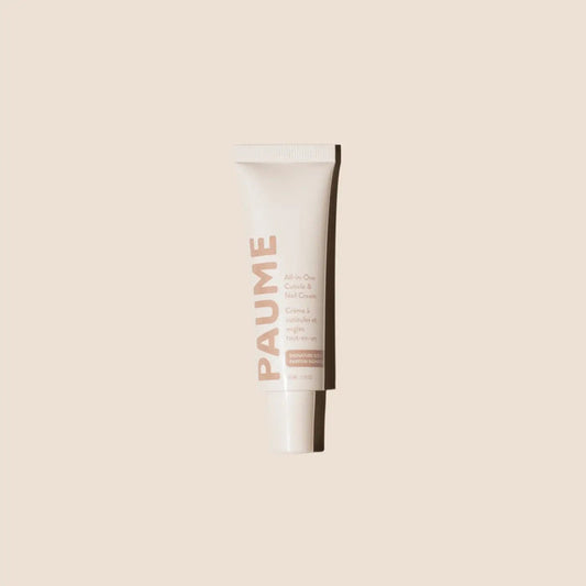 A tube of PAUME - ALL IN ONE CUTICLE AND NAIL CREAM by PAUME, infused with plant-based keratin, stands upright against a light beige background, showcasing minimal modern packaging in soft pink and white.