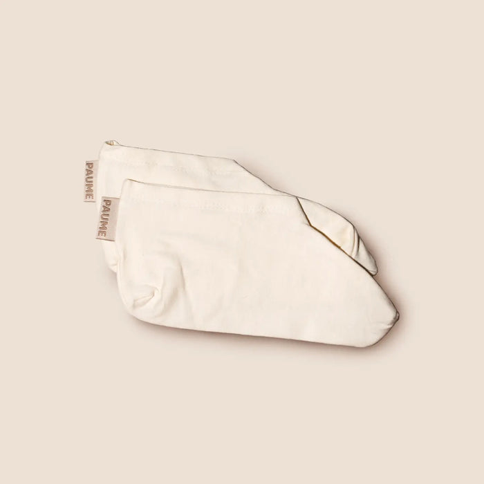 A pair of folded, off-white PAUME - COTTON OVERNIGHT SOCKS with beige "PAUME" tags, shown on a matching beige background.