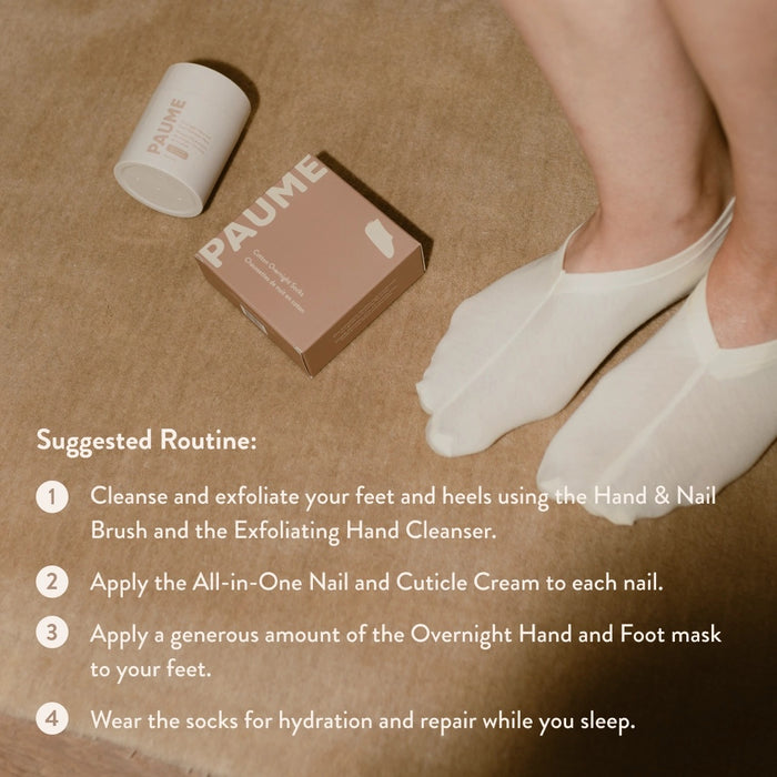 A pair of folded, off-white PAUME - COTTON OVERNIGHT SOCKS with beige "PAUME" tags, shown on a matching beige background.