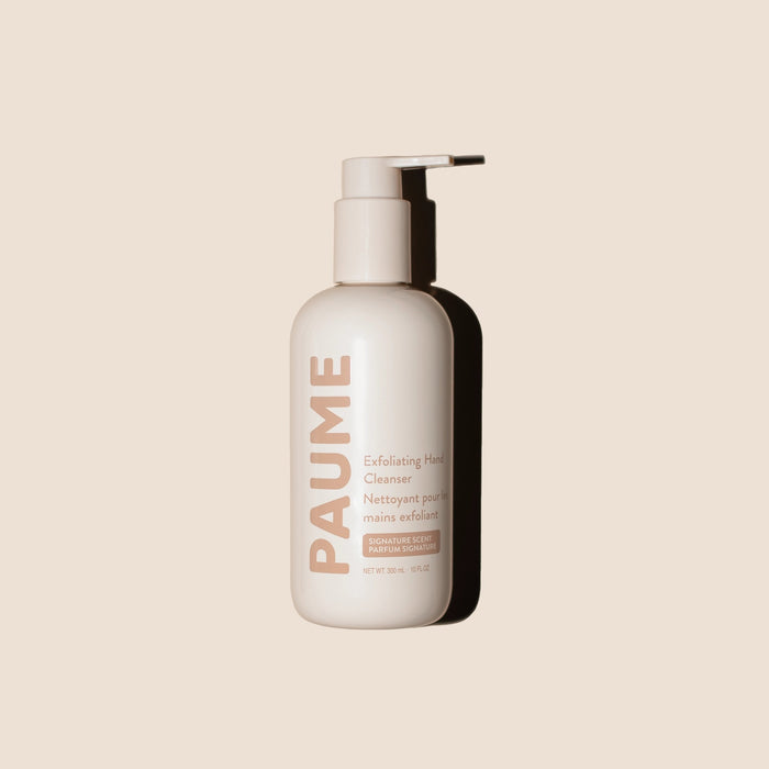 A person dispenses foam from a white PAUME - EXFOLIATING HAND SOAP bottle onto their hand under a sink. Text highlights it's free of parabens, sulfates, and silicones, with icons for vegan, cruelty-free, natural, and sustainable.