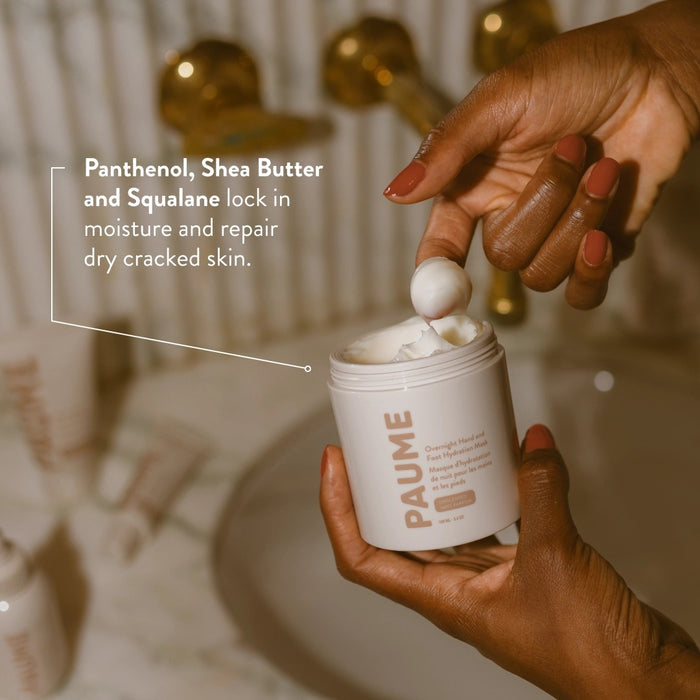A white cylindrical container of PAUME - OVERNIGHT HAND AND FOOT HYDRATION MASK stands upright on a beige background. The minimalist packaging, featuring beige text and a clean design, is ideal for sensitive skin.