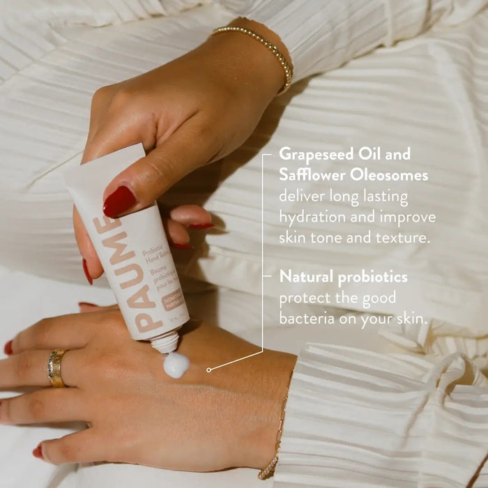 The PAUME - PROBIOTIC HAND BALM 2OZ stands upright with a beige cap on a matching background, featuring minimalist packaging with "PAUME" vertically and enriched with natural probiotics for anti-aging care.
