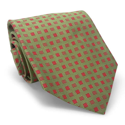 The PETER-BLAIR Bespoke Small Squares Silk Tie in Green by BIRD DOG BAY features a geometric red square pattern and is handmade in New York, shown rolled up on a white surface.
