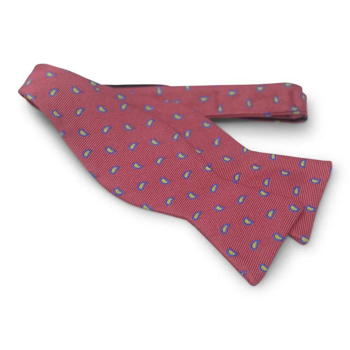 The BIRD DOG BAY PETER-BLAIR Cape Cod silk bow tie in red is handmade with a ribbed texture and features evenly distributed small blue and yellow paisley motifs. Adjustable for a perfect fit.