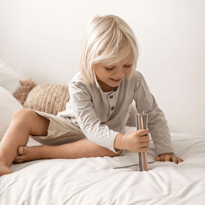 Child playing with colorful Pick Up Sticks game, enhancing fine motor skills and family fun.
