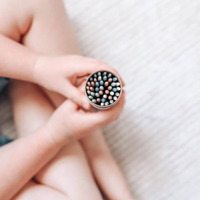 A child's hands holding a container of colorful Pick Up Sticks for a fun family game.