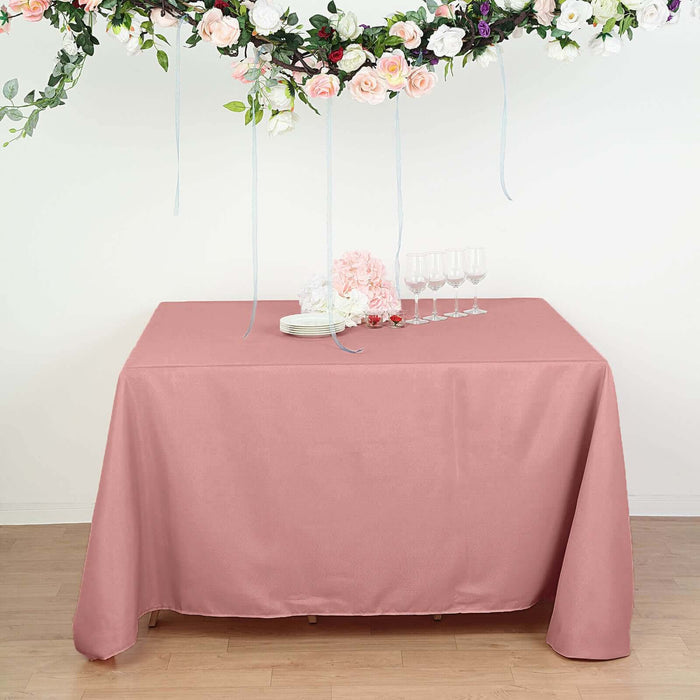 Pink tablecloth draped over a table with floral decor and glassware.
