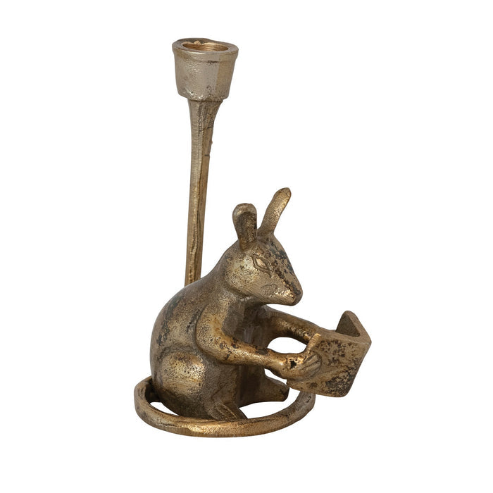 The READING MOUSE CAST ALUMINUM TAPER HOLDER by CREATIVE COOP features a charming mouse reading upright in an antique gold finish, with a candle holder above its head—a playful accent for your space.
