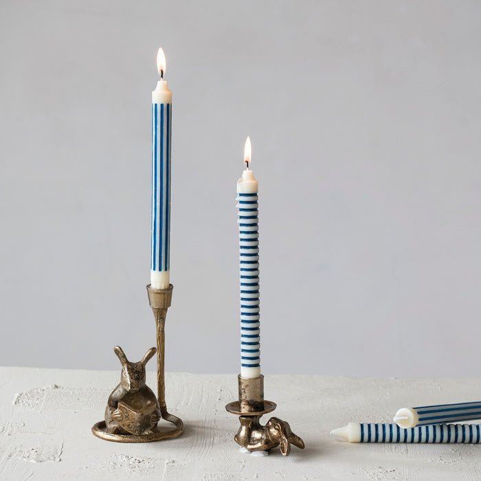 The READING MOUSE CAST ALUMINUM TAPER HOLDER by CREATIVE COOP features a charming mouse reading upright in an antique gold finish, with a candle holder above its head—a playful accent for your space.