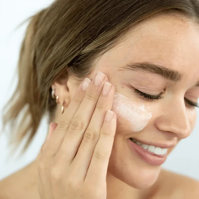 Woman applying cream to her face with a blurred background