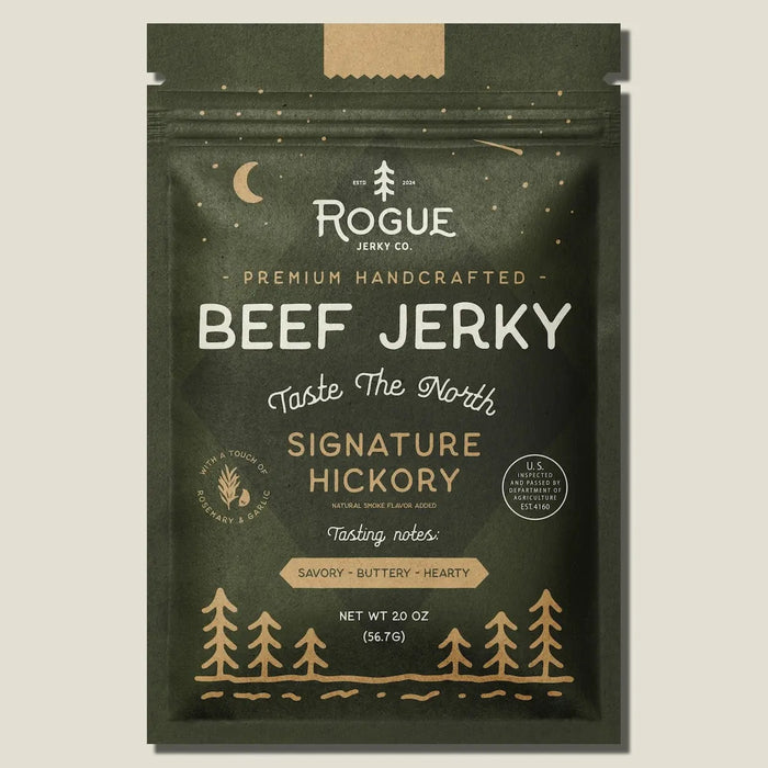 A dark green pouch of ROGUE JERKY - HICKORY BEEF JERKY by ROGUE JERKY CO., featuring forest and moon imagery, labeled “Premium Handcrafted” and “Taste The North.” This savory, buttery, hearty sugar free jerky is an ideal keto friendly snack. Net weight: 2 oz.