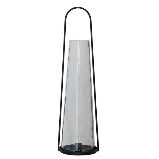 The ROUND METAL LANTERN TAPER HOLDER WITH HAMMERED GLASS HURRICANE by CREATIVE COOP features a tall, black metal frame and a cone-shaped hammered glass hurricane for a modern, minimalist look with sleek lines and transparent materials.