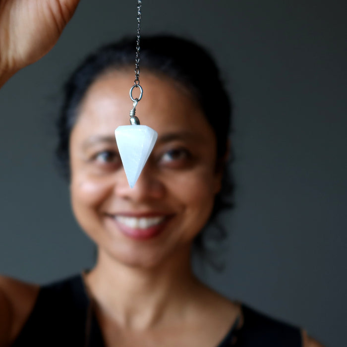 woman holding white selenite pendulum