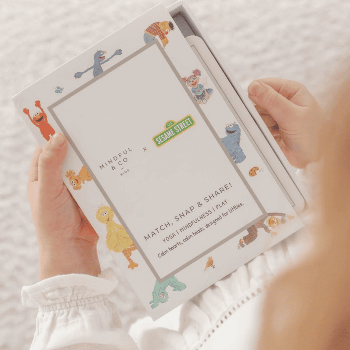 Child holding the Sesame Street 3-in-1 Card Game box featuring colorful characters and game instructions.