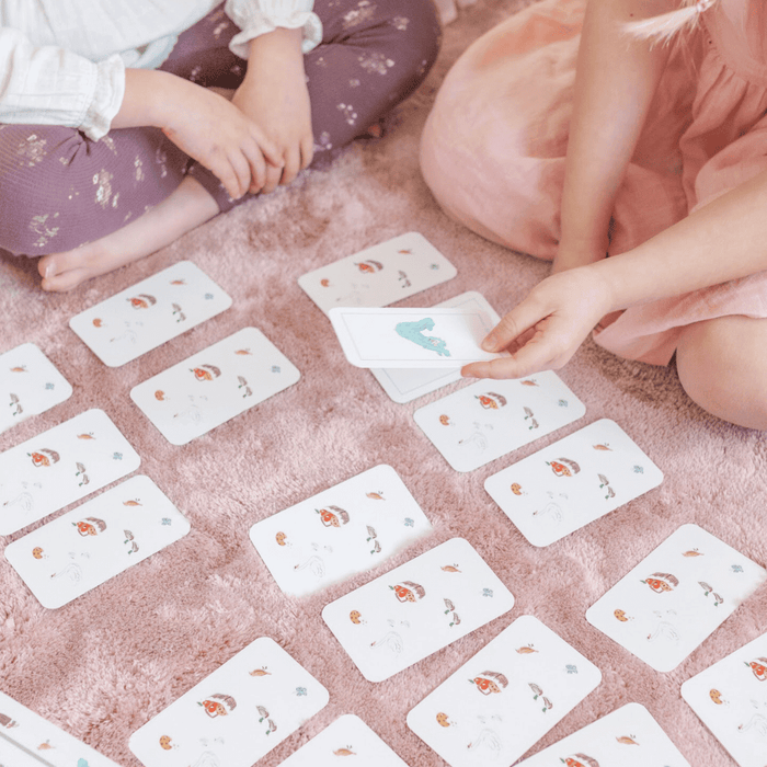 Children playing the Sesame Street 3-in-1 Card Game on a soft rug with colorful cards spread out.