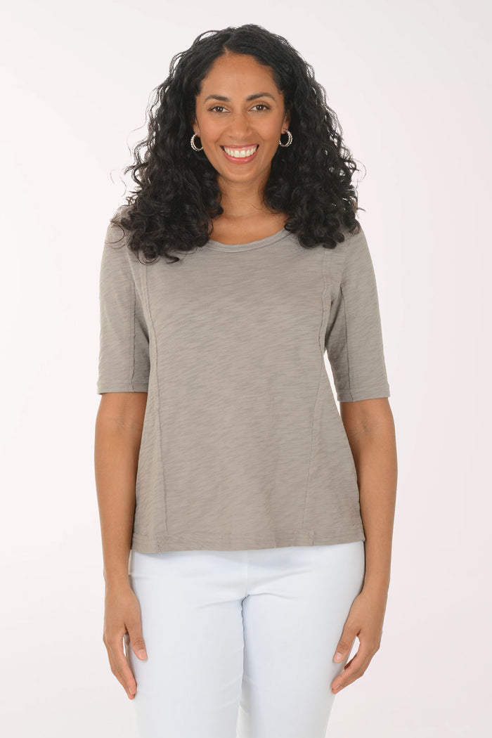 Woman wearing a gray top and white pants on a white background