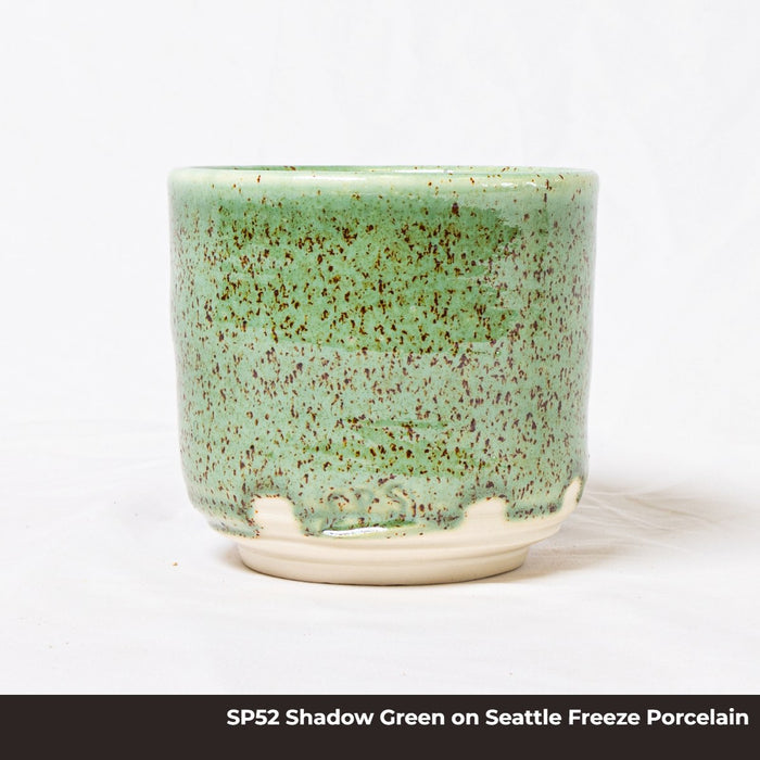 Cup in SP52 Shadow Green glaze on Seattle Freeze porcelain, bright speckled green over a white unglazed foot