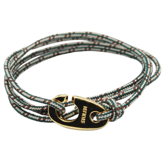Sitting outdoors in sunlight, a person in a white shirt holds a cup while wearing the STOLEN RICHES BYRON Rope Bracelet with Gold Brummel Hook—a stylish, waterproof accessory. Blurred urban scenery forms the backdrop.