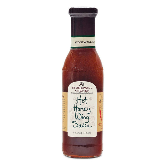 A bottle of STONEWALL KITCHEN - HOT HONEY WING SAUCE, featuring a beige label with green accents and standing upright on a white background, offers the perfect balance of sweet heat for anyone who enjoys a spicy wing sauce.