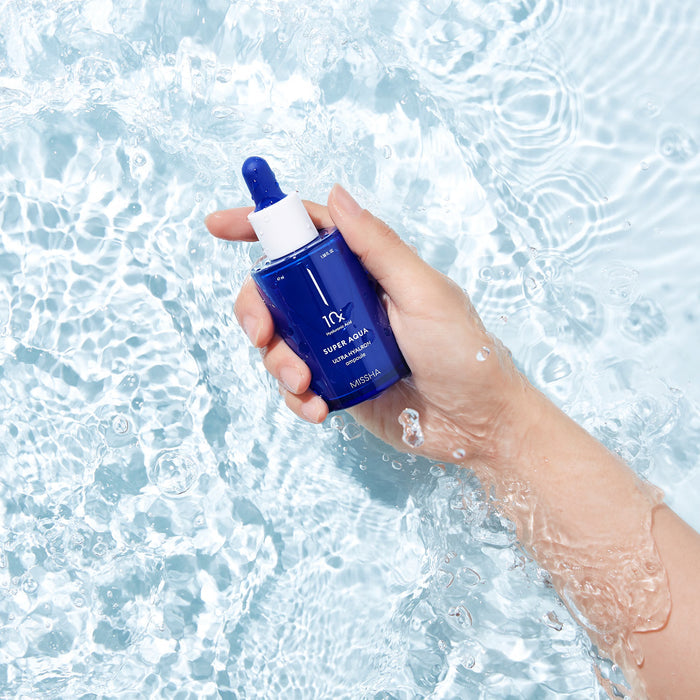 A blue glass ampoule with a dropper, labeled 'Missha Super Aqua Ultra Hyalron Ampoule in a pool of water