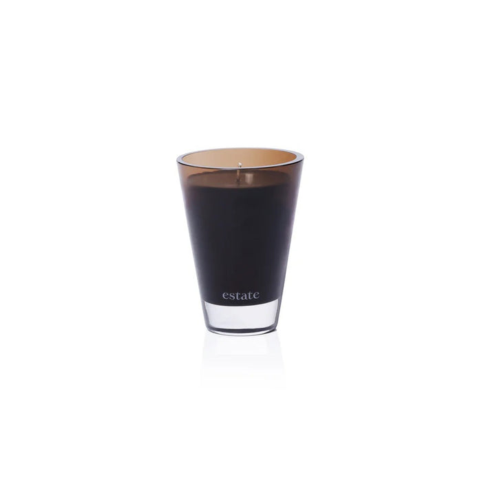 The ZODAX Thistle Estate Candle (10.5 oz) in black is displayed in a glass holder beside its matching box, both reflecting the fresh California coast fragrance.