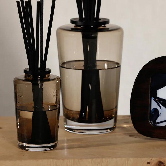 A black rectangular ZODAX gift box with a small label sits beside the THISTLE ESTATE DIFFUSER - 200 ML, featuring black reeds and scented liquid for a refreshing California coast fragrance.