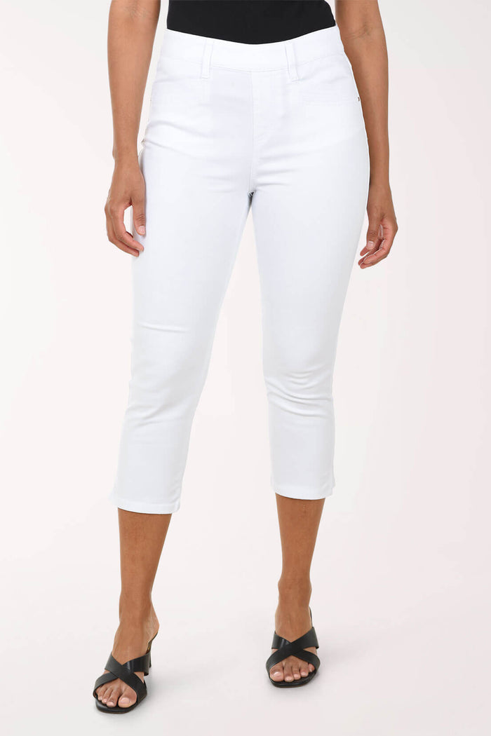Woman wearing white capri pants against a light pink background
