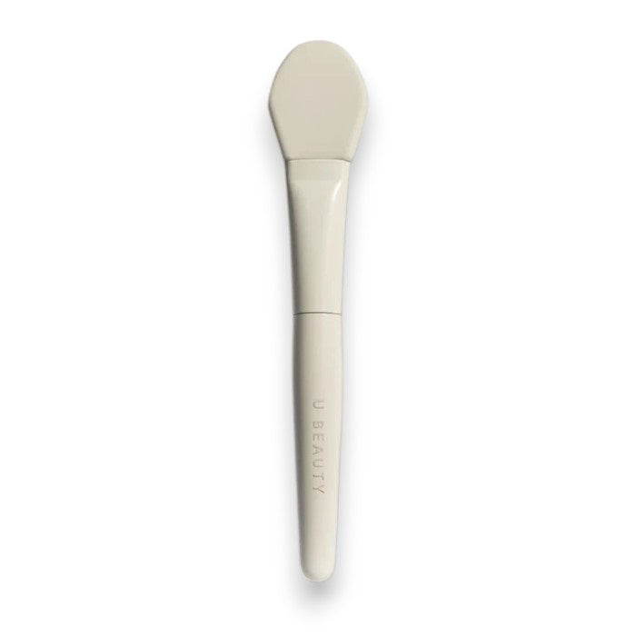THE BRUSH by U BEAUTY is a white silicone skincare applicator featuring a flat, rounded tip and "U BEAUTY" on the handle—crafted for precision application against a clean, white background.