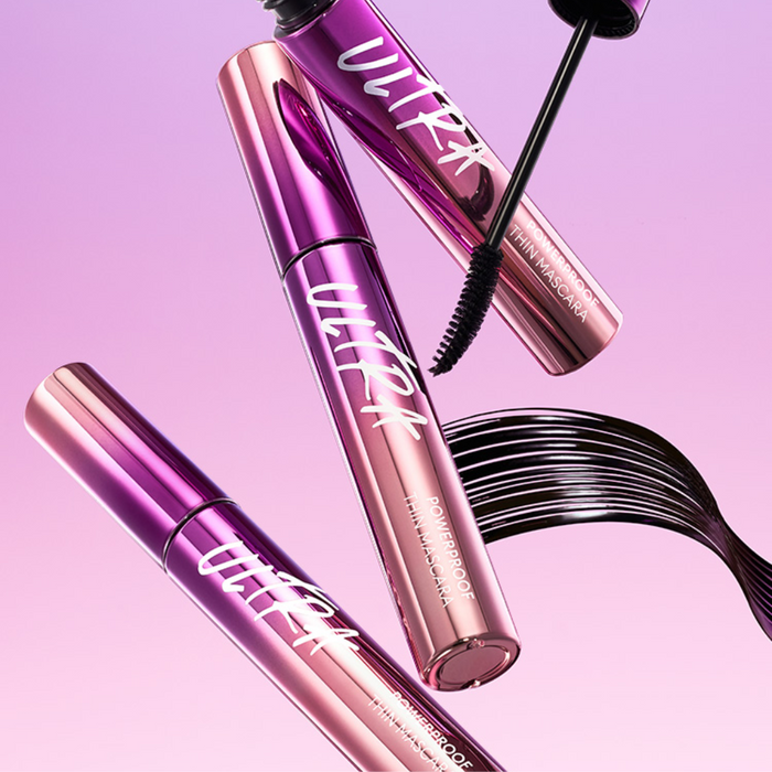 A tube of MISSHA Ultra Powerproof Thin Mascara with a brush, displayed on a reflective surface with a colorful, holographic background.