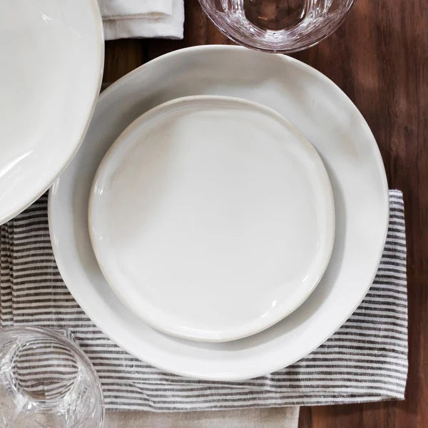 The VIETRI - FORMA CLOUD DINNER PLATE by VIETRI is a handcrafted white stoneware plate with subtly wavy, uneven edges, shown from above against a white background.
