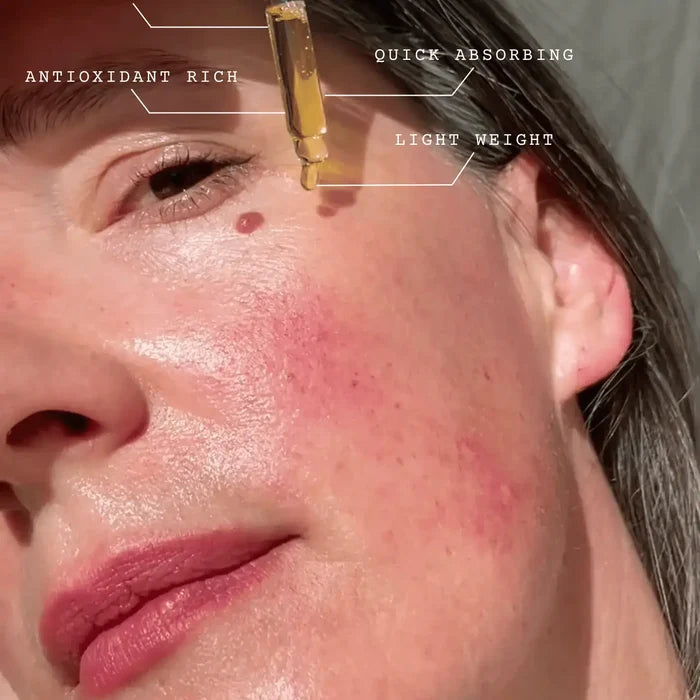 Close-up of a woman's face with a dropper applying a product, labeled for features.