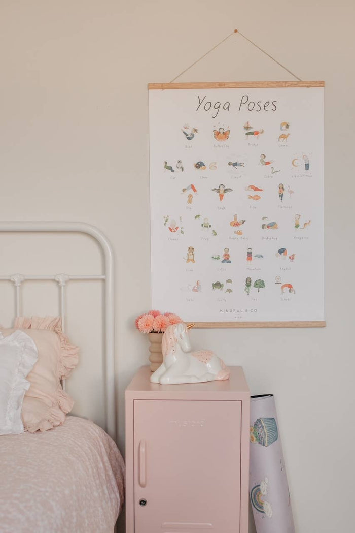 Yoga Poses Print on a wall above a pink nightstand with flowers, showcasing fun yoga poses for kids.