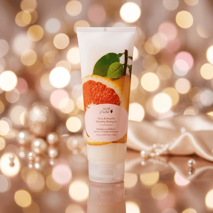 Tube of shampoo with grapefruit and leaf design on a blurred lights background
